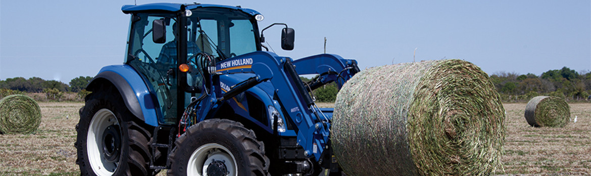 New Holland tractor moving hay bails.